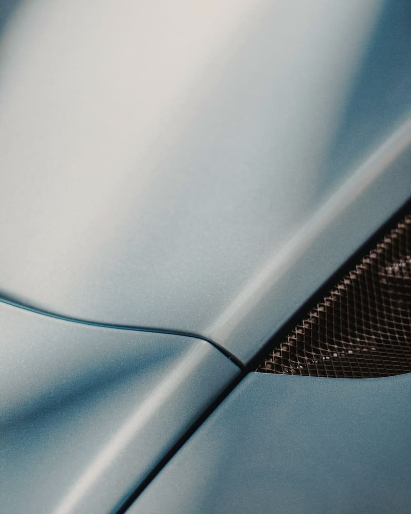 Daylight running along the sculpted body line of a blue hood
