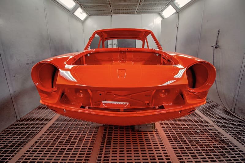 Freshly refinished red body shell drying inside a paint booth