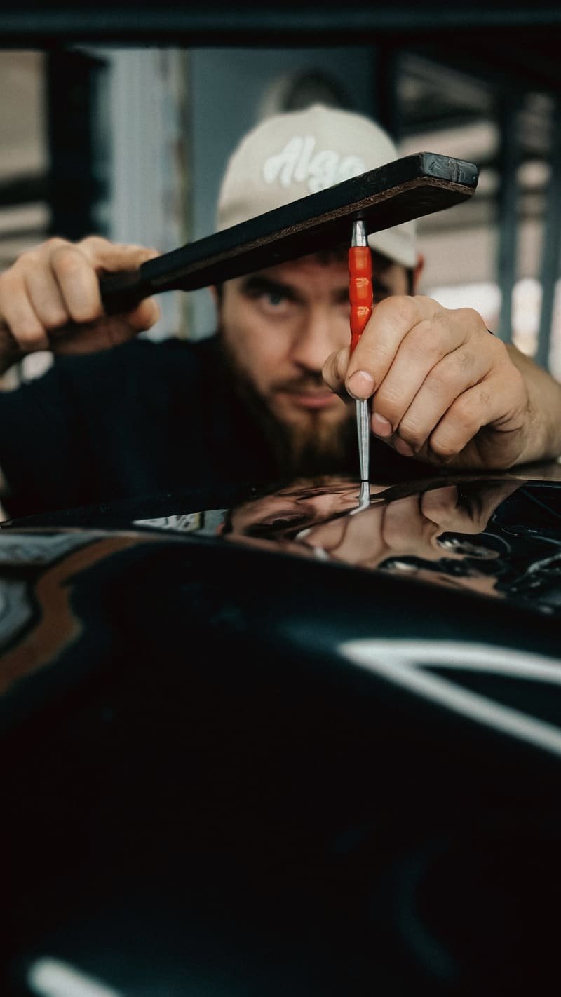 Technician crouching to sight along the surface of a black panel