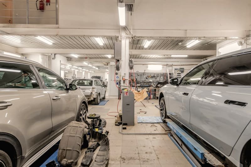 A row of vehicles under repair, parked side by side inside a workshop