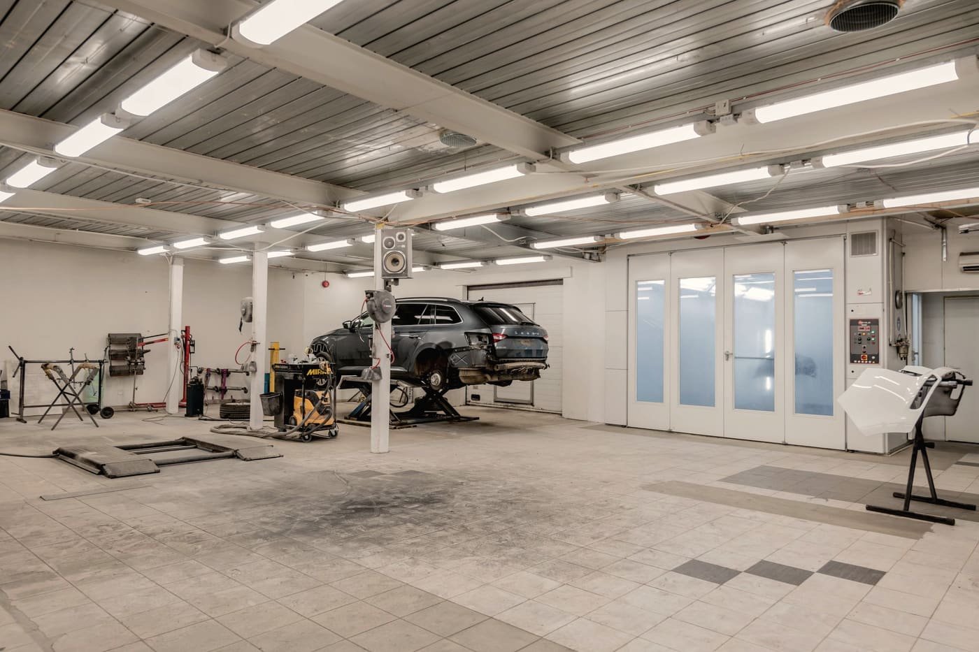 Repair bay with a vehicle raised on a two-post lift and open floor space around it