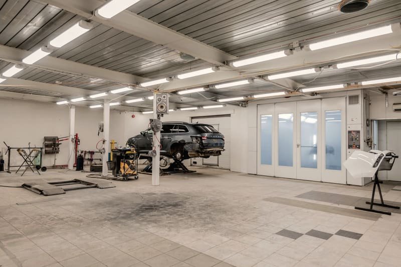 Open repair bay with a vehicle raised on a two post lift and clear floor space around it