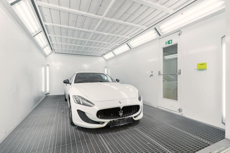 White coupe photographed side on inside a bright booth