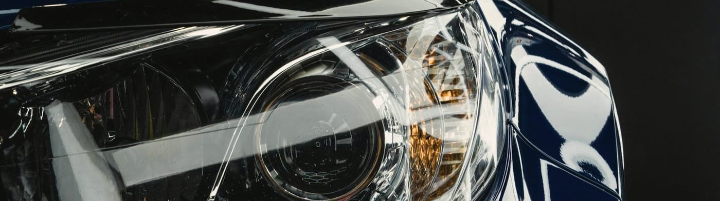 Reflections streaking across the glossy dark blue paint of a repaired front fender and headlight