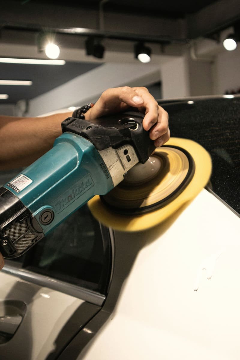 Rotary polisher with a yellow foam pad working across white paint